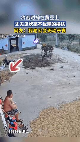 11月5日报道，浙江农家小院里，妻子提着黑色塑料袋往门口走，光着膀子坐在板凳上的