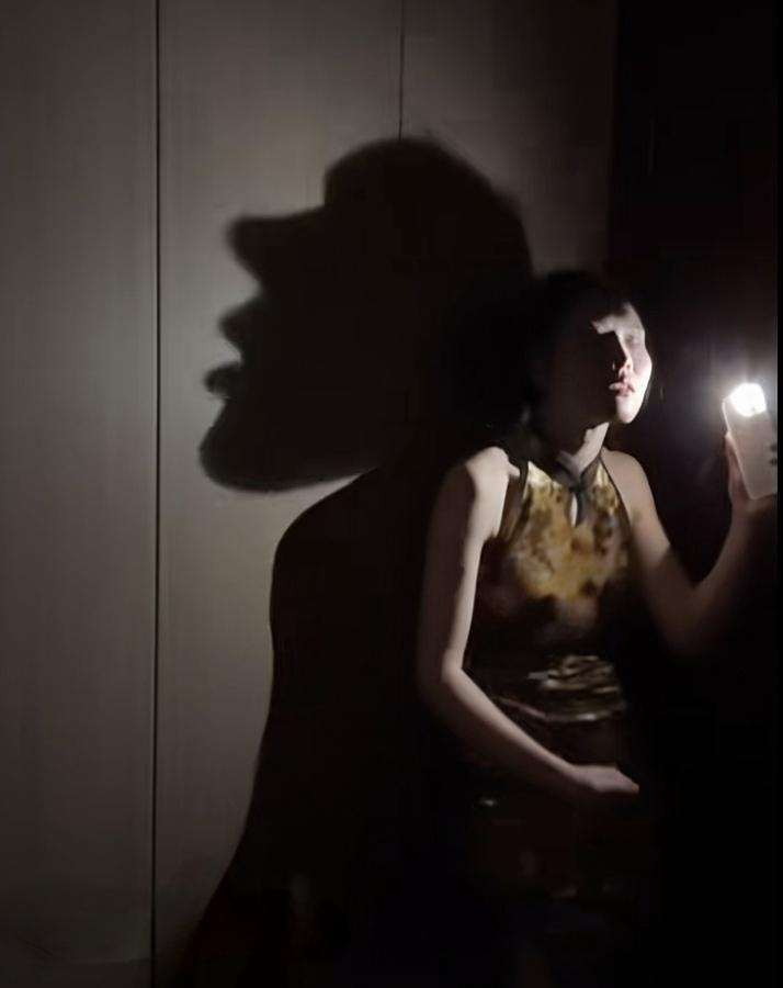 记录美好的图片如图这位美女真是一位天才！她在黑暗中用手机手电筒照着自己唱歌，墙上