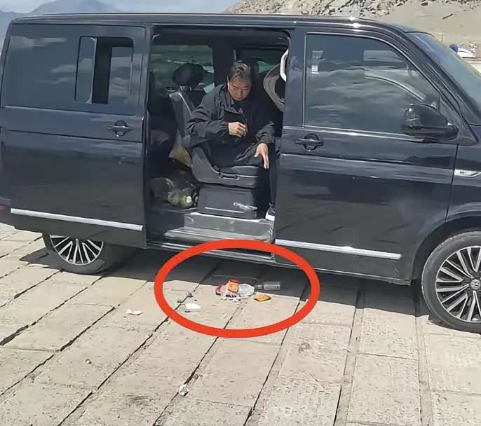 网友在新疆旅游时拍下的一幕：在新疆某旅游景区的停车场，一位中年男子在清理车上的垃