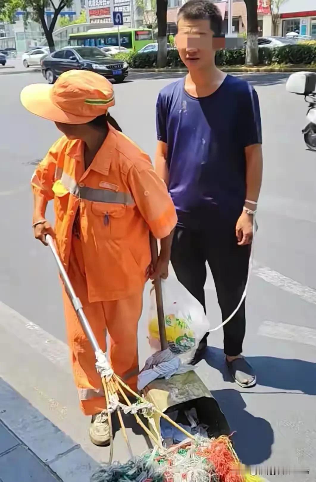 西安一位环卫工阿姨40度高温下打扫卫生时，用一根绳子将自己与三十多岁弱智儿子牵在