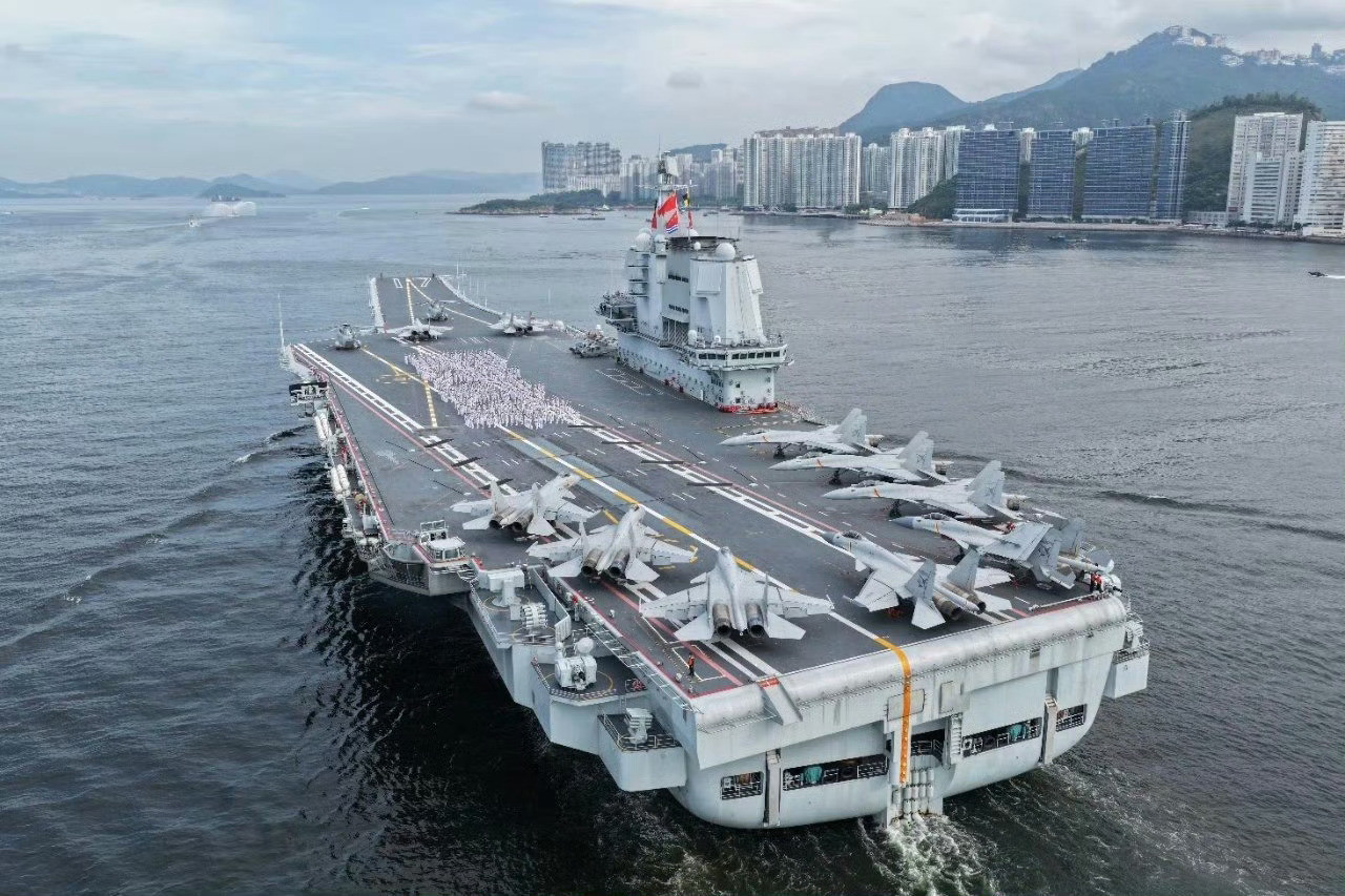 山东舰飞行甲板上，10架舰载战斗机列阵，700余名海军官兵身着白色海军军装，列队