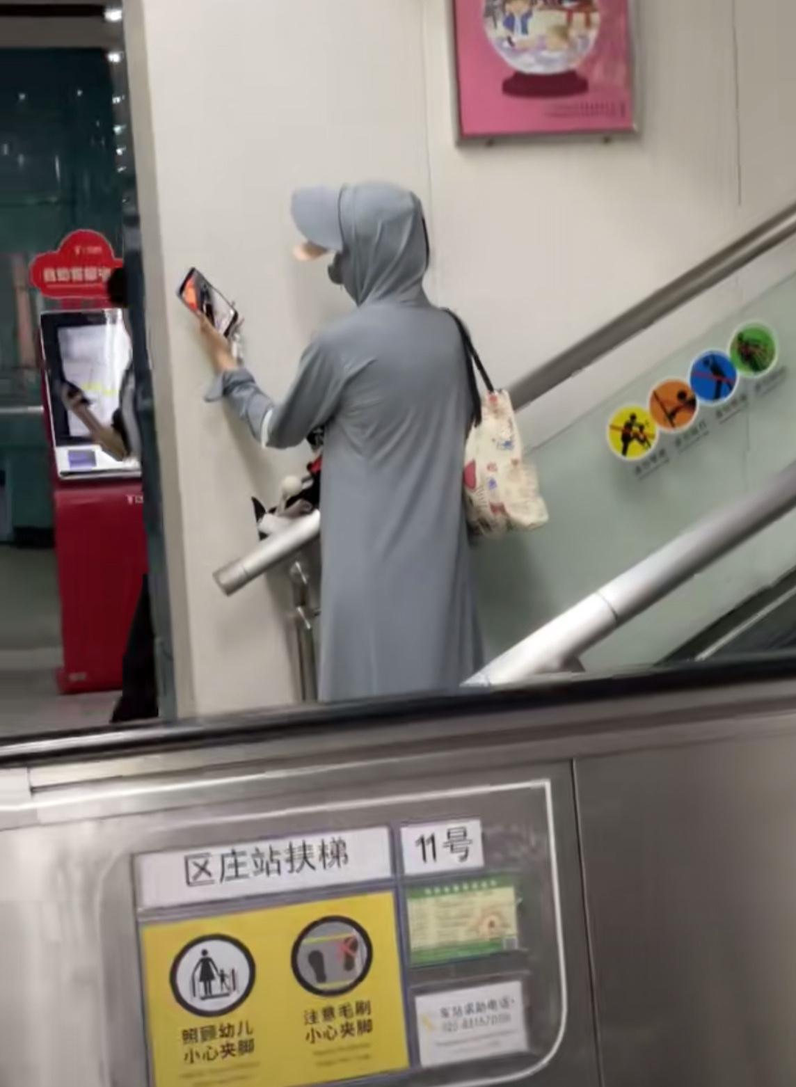 在地铁站撞见这位裹得严严实实的大姐，从头到脚防晒衣捂得密不透风，举着手机对着角落