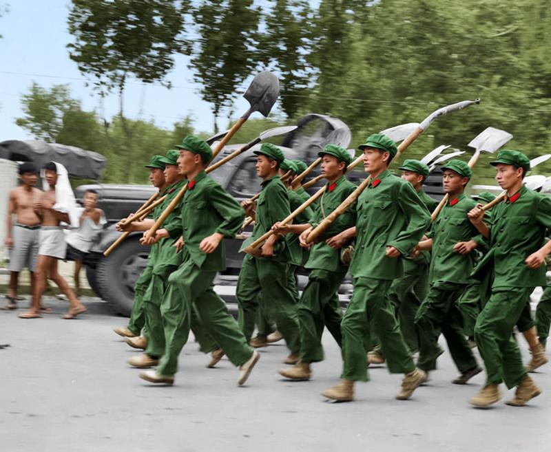 1976年，唐山地震后的黑白照一队解放军战士穿着略显褶皱的军装，每人肩上都扛着铁