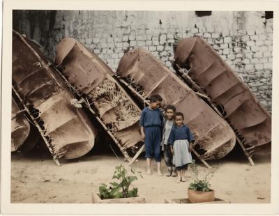 1930年江古城墙下，三个藏族孩童站在倒扣的牦牛皮船前，以稚嫩的身影，衬着高原特