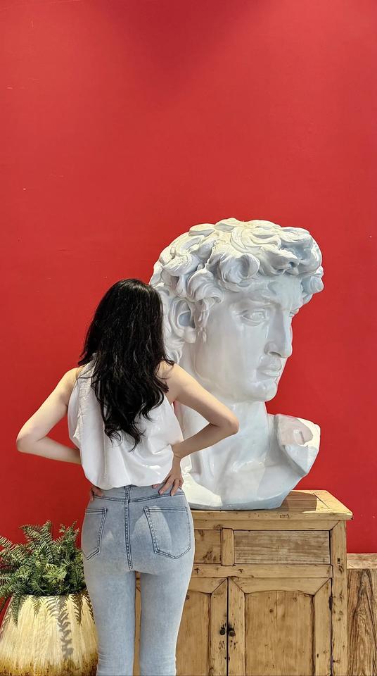 复古风穿搭，牛仔牛仔裤搭配白色上衣，与红色背景的雕塑相得益彰。分享一下你的穿搭