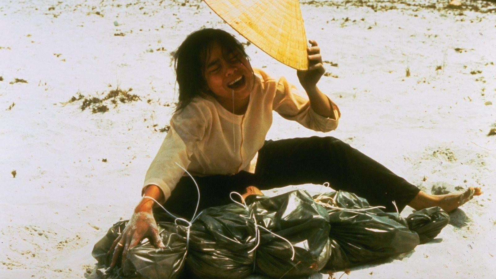 1969年4月，在古城顺化附近，一位年轻的南越女子跪在沙地上，她身前的塑料