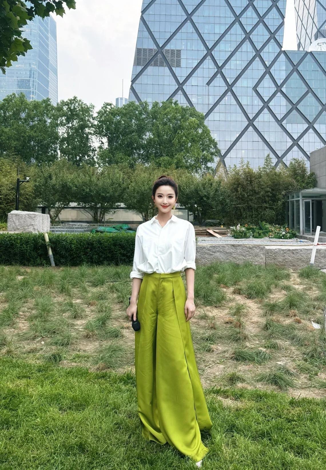 央视主持人刘心悦在央视办公大楼前的留影照。长相甜美，身材高挑，气质清新靓丽，主持