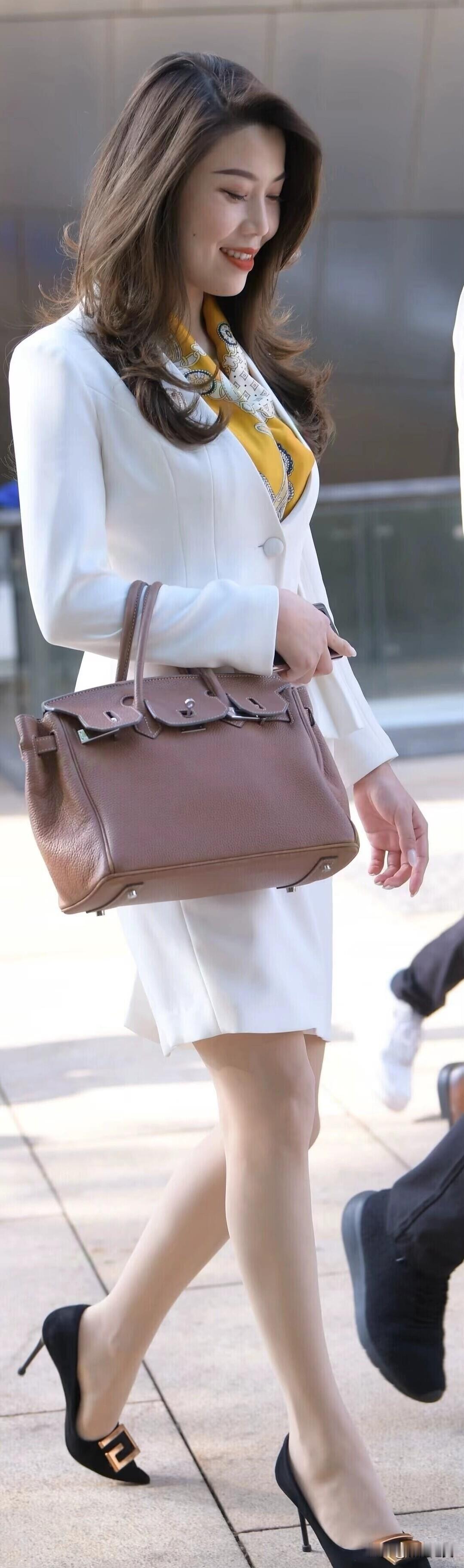 白色西装套裙搭配黄色丝巾，优雅又干练！棕色手提包与黑色高跟鞋加持，职场女性的精致