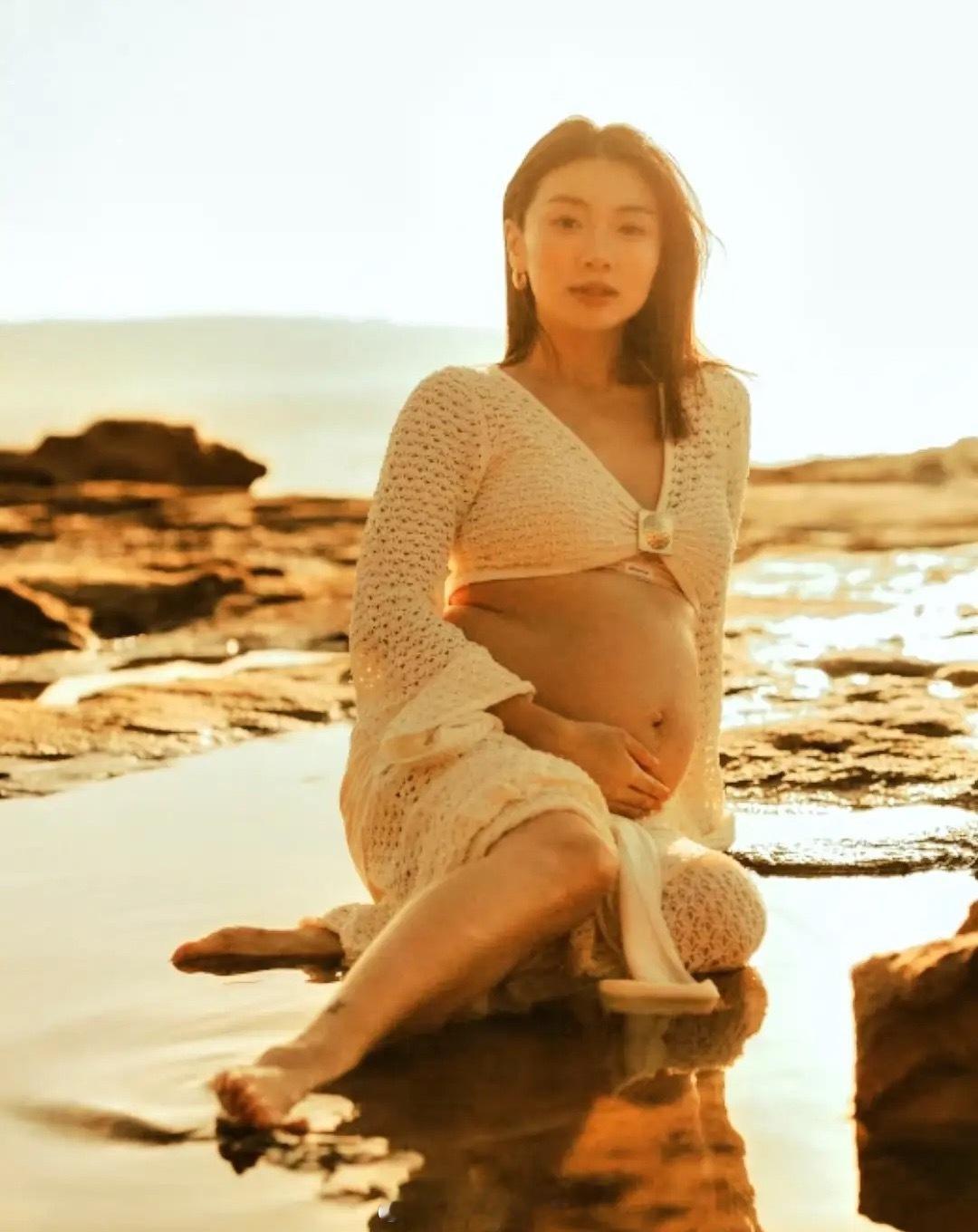 36岁程晓玥晒二胎孕妇照，挺着肚子坐在海边沙滩上，太拼了！第二次怀孕明显胖了不少