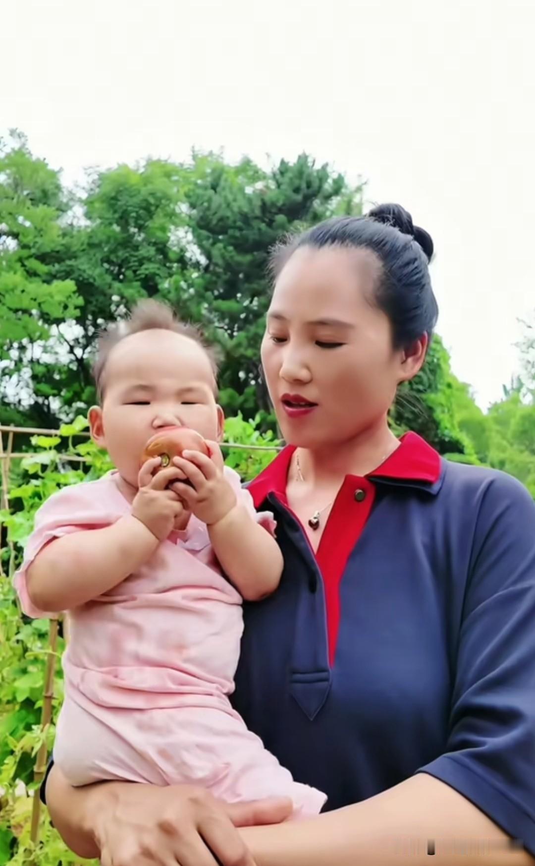 耿为华老师今天在小菜园里摘了个大西红柿给二宝吃，妈妈看着漂亮的小宝贝吃西红柿的样