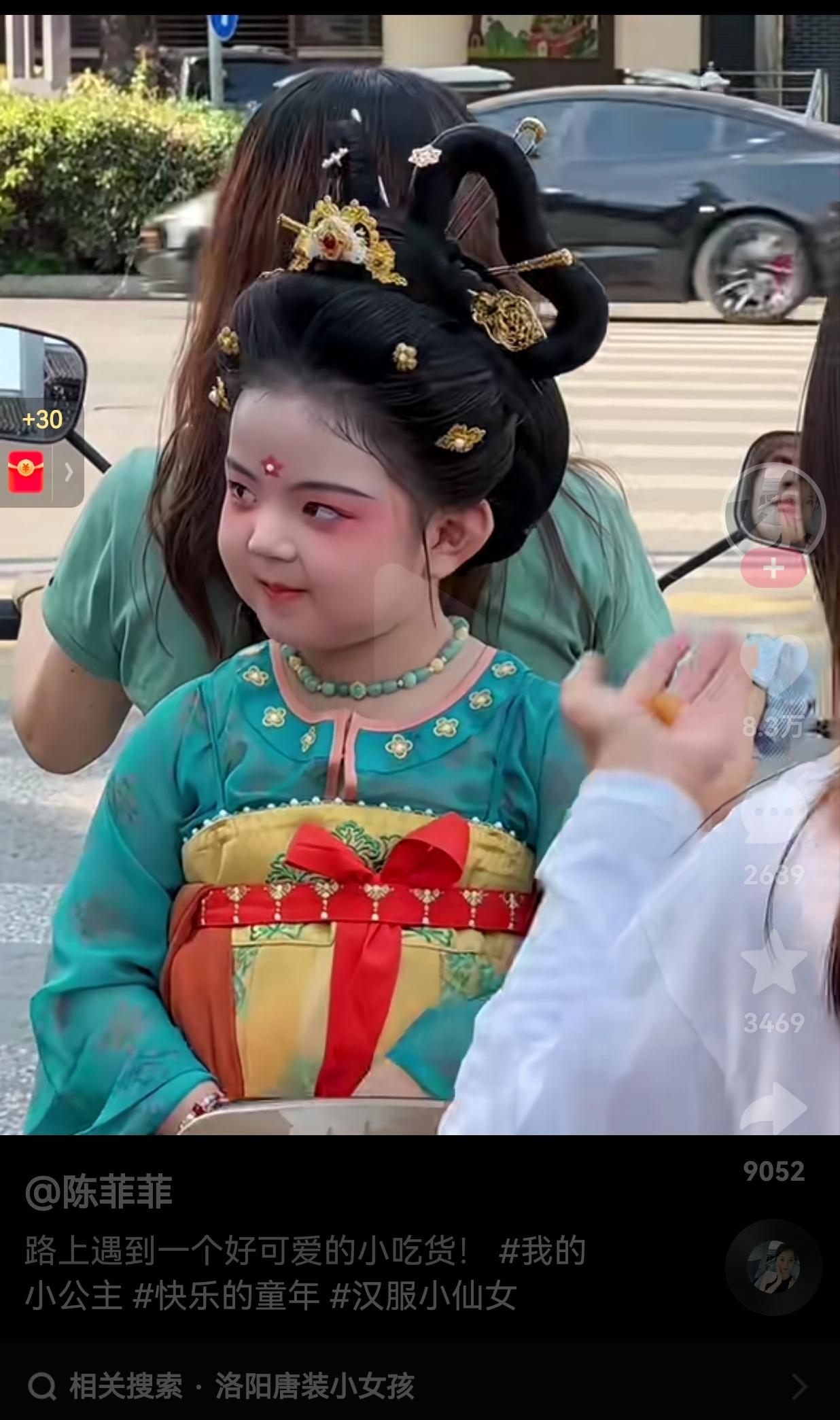 这也太贪吃了吧？一女子骑电动车偶遇穿唐装小女孩，小女孩坐在家长的电动车上，双方正