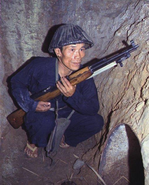 1968年，一名越南游击队战士脚踩拖鞋，手持西蒙诺夫半自动步枪步枪，蹲在地道口伏