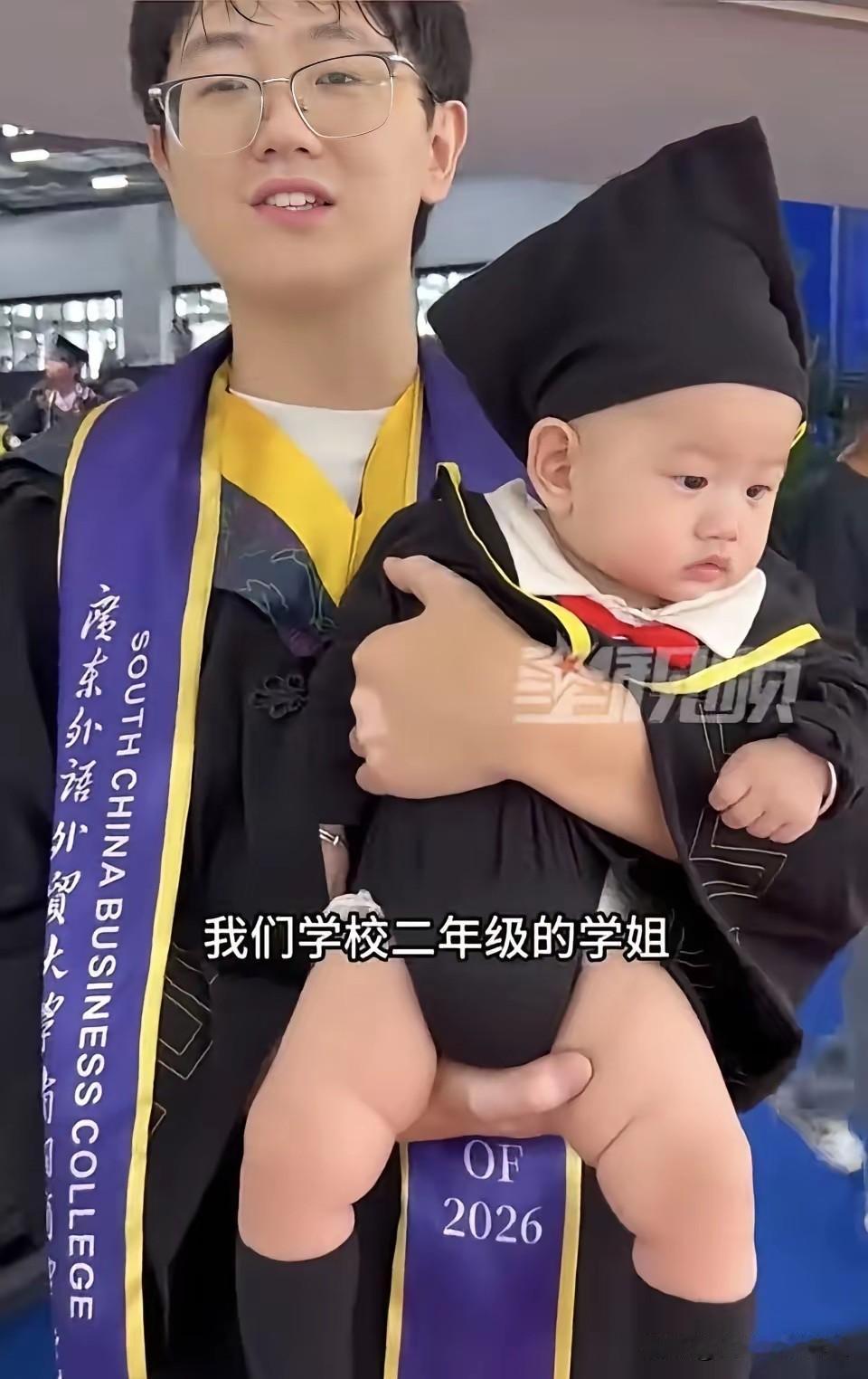 广外毕业典礼这幕真炸了——计算机系张同学抱着没满周岁的娃上台拨穗，小家伙穿的迷你