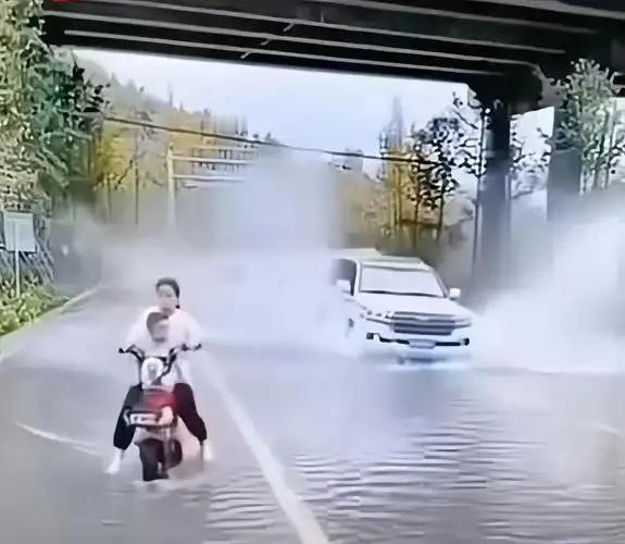 12月20日，湖北省黄冈市一男子骑电动车带女儿回家，在路过一低洼处时，一辆黑色汽