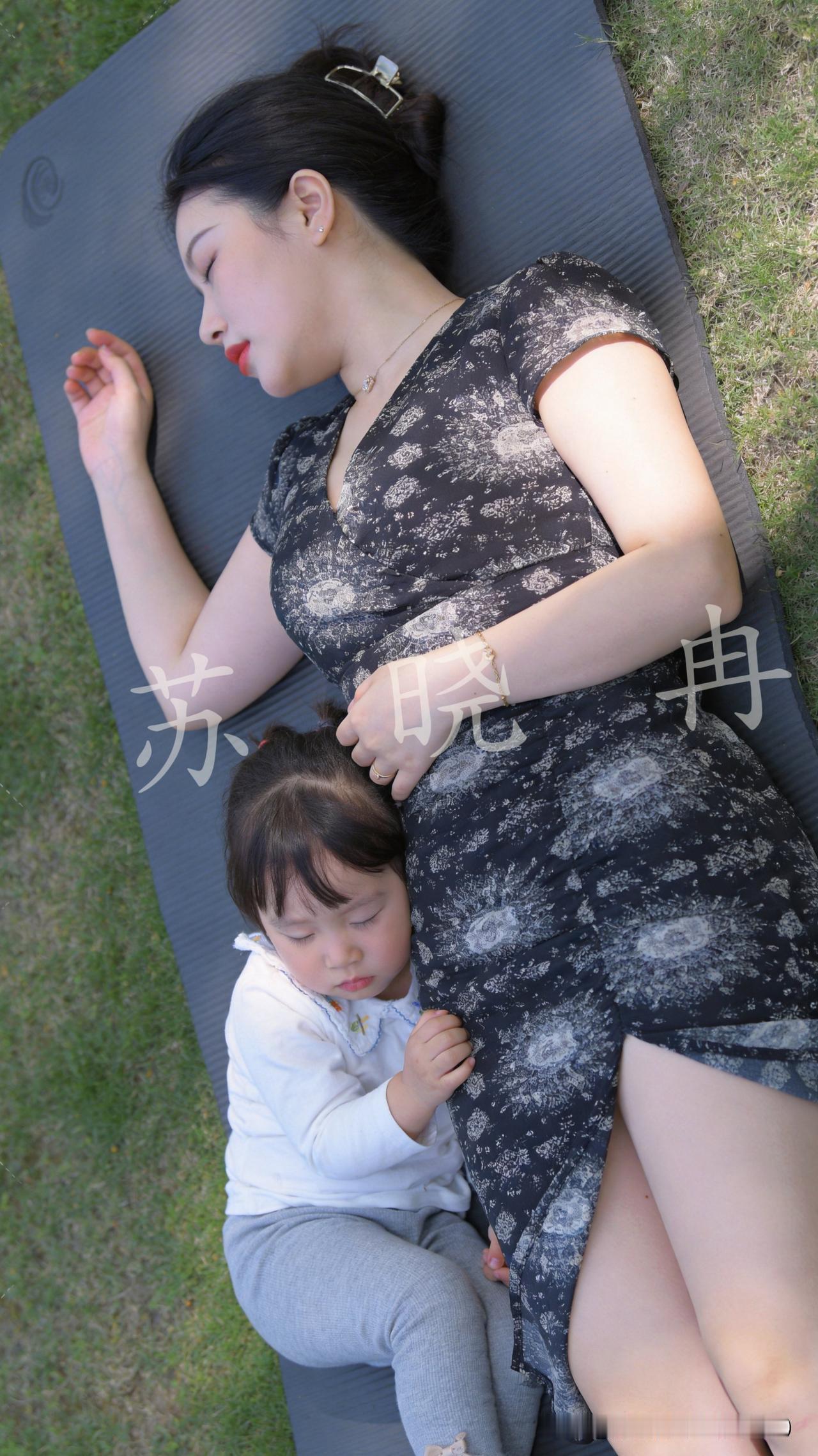 这一幕，是时光落笔的温柔画卷。以青草地为笺，以暖阳为墨，以母子相依为笔，晕开