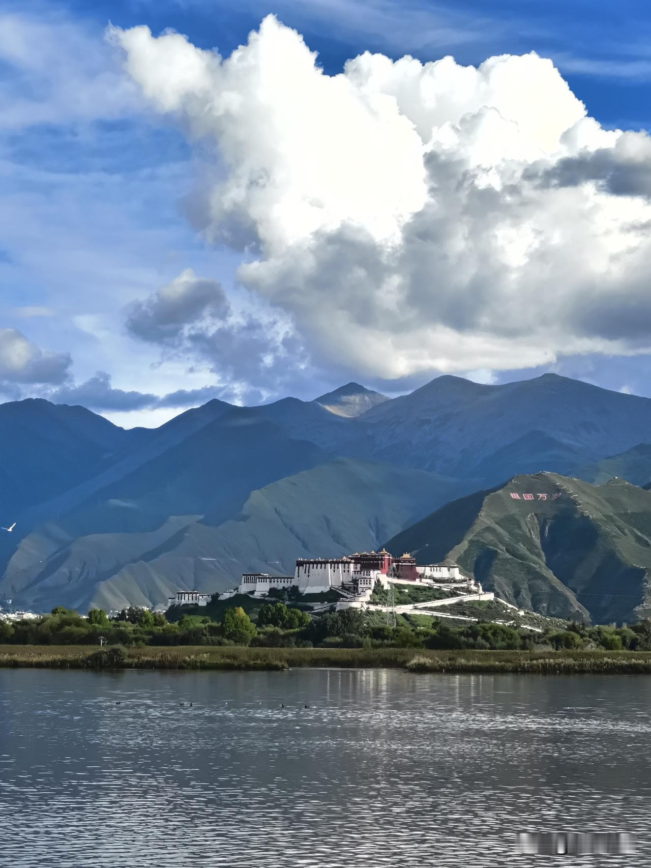 静立拉鲁湿地湖畔等候夕阳，湖水平缓如镜，布达拉宫静卧对岸群山之间。层层山峦绵延起