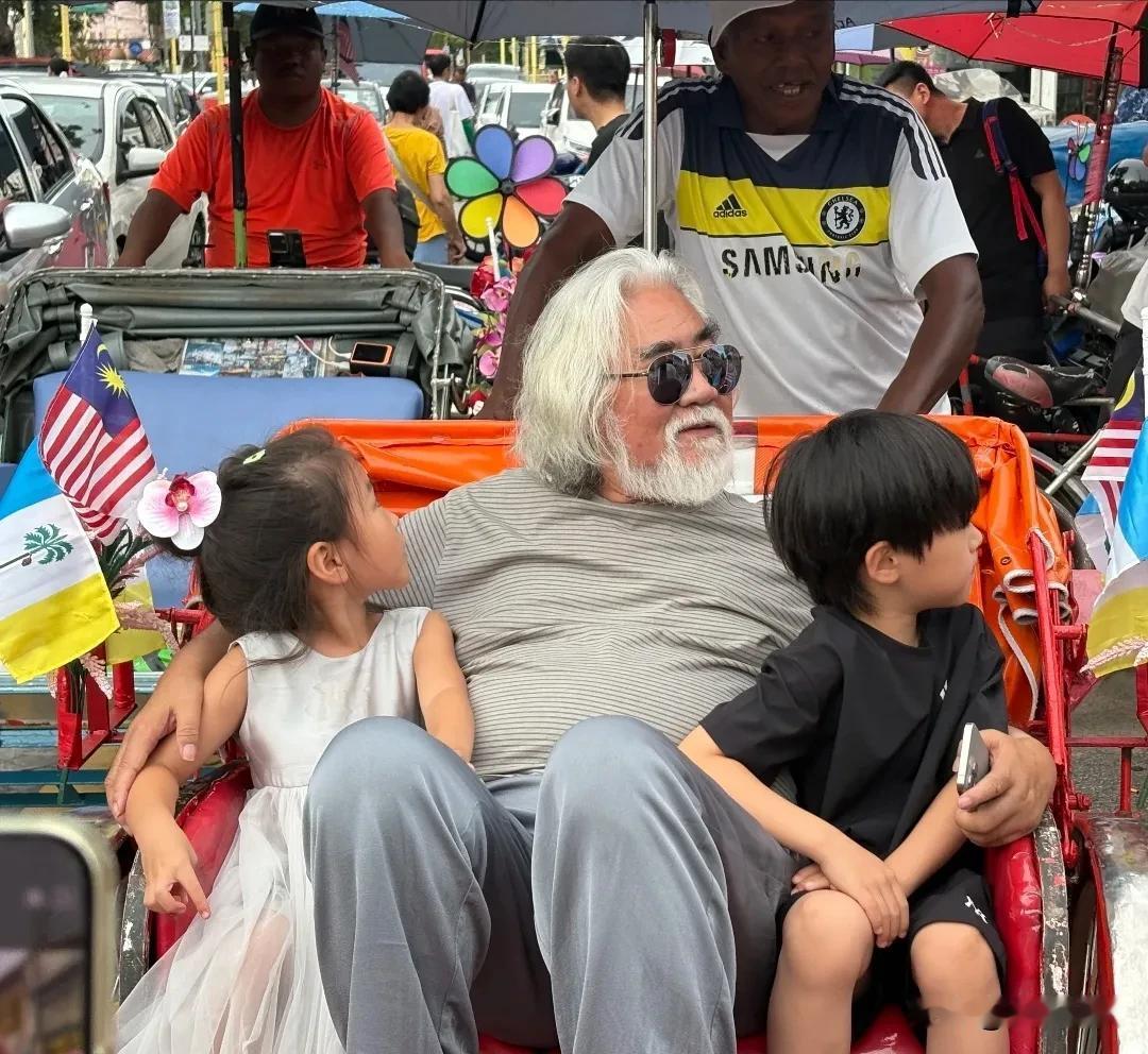 张纪中带着老婆孩子去马来西亚槟城度假，体验当地的人力车。74岁的张导须发皆白，