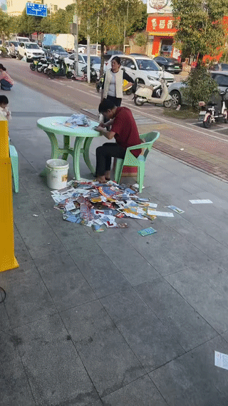 这位大哥真是太想中大奖了！只见他买了一大堆的“刮刮乐”彩票，坐在椅子上不停的刮