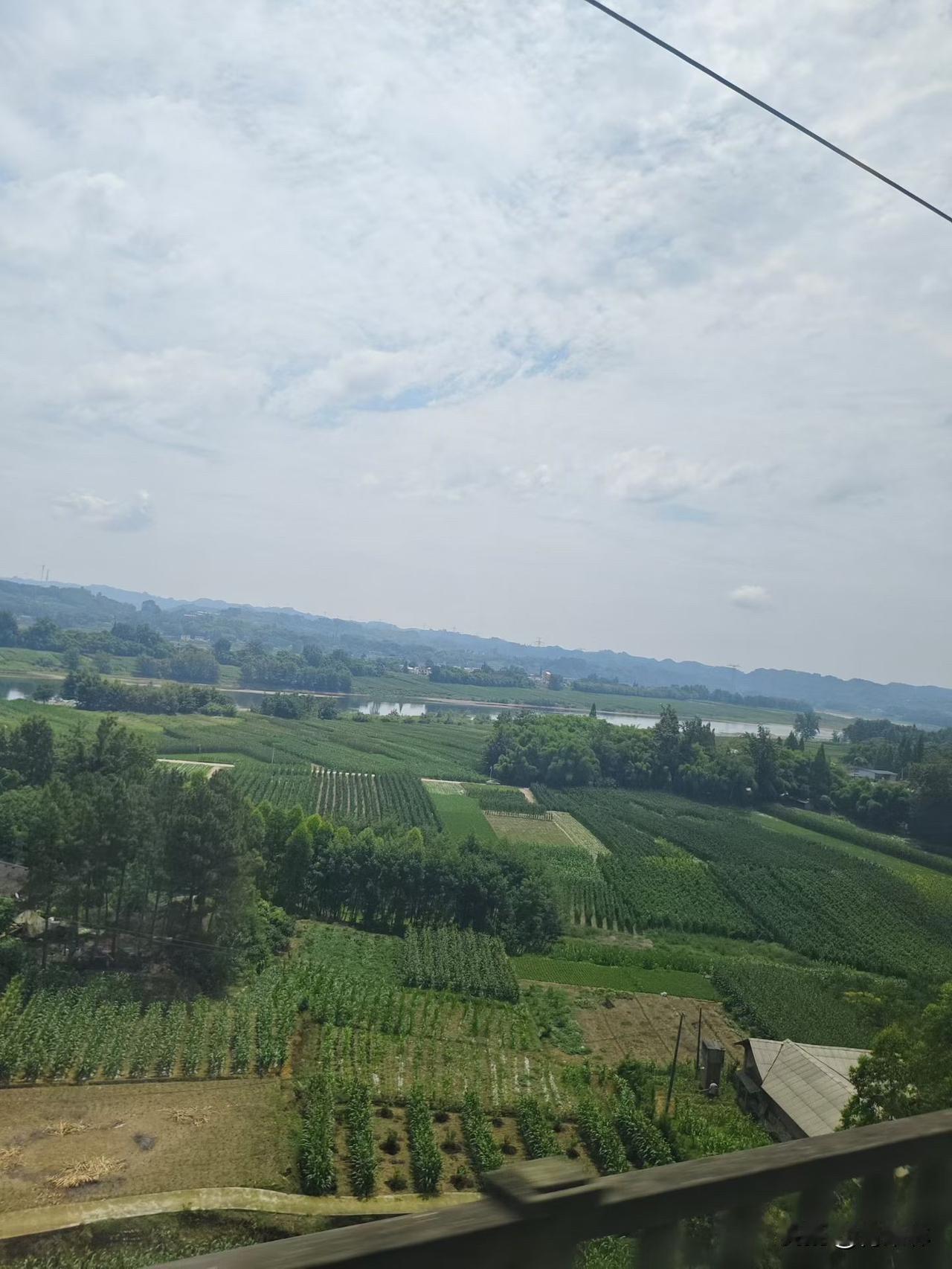 旅行途中随手拍下窗外的山野风光，蓝天白云铺在连绵青山之上，蜿蜒小河绕着田园村落，