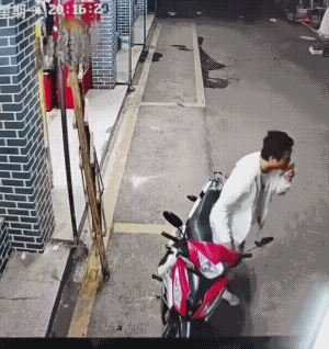 小伙子停下摩托车后，下来刚站好，就被倒下的梯子砸中了头和肩膀。实话实说，若不是