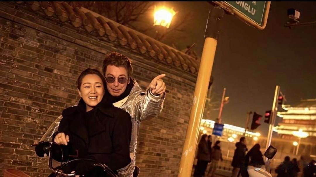 巩俐骑着自行车，带着外籍丈夫漫步游览北京，画面闲适又接地气。