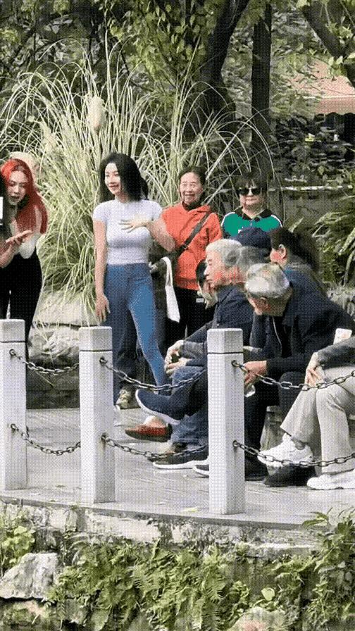 女子身材妖娆妩媚，尽情地展示她前凸后翘的好身材，吸引了众人的目光。公园的一角，