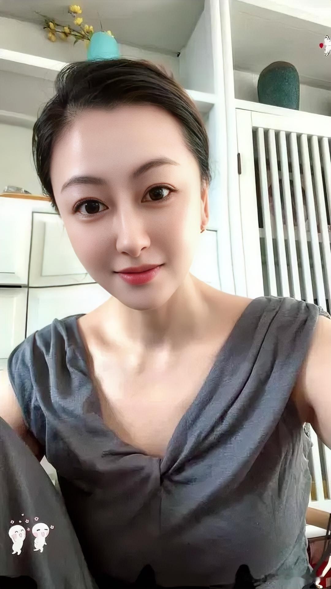 灰衫素雅，发髻温婉。眉眼清澈似水，浅笑盈盈，透着恬淡与从容。室内光影柔和，尽显日