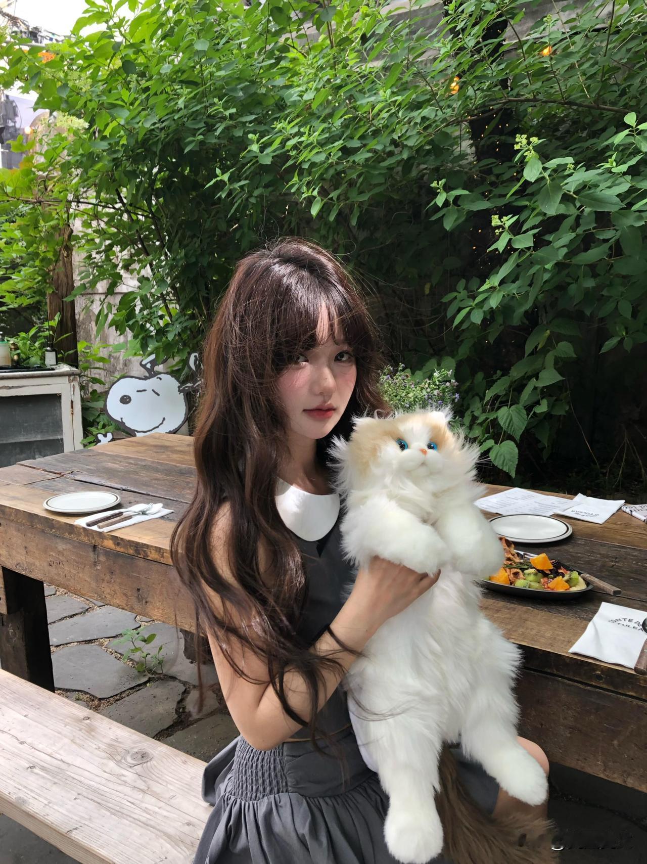 在绿意盎然的户外，抱着可爱的毛绒猫咪，享受宁静的午后时光。