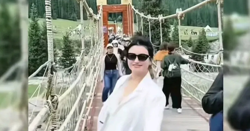 这是新疆昭苏一景区吊桥断裂前一秒的画面，一位身穿白西装戴着墨镜的年轻漂亮的女生正