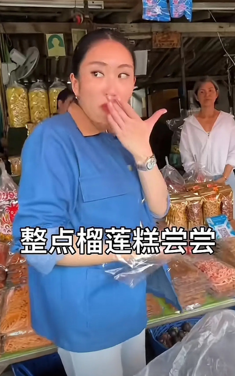 泰国女总理当场吃榴莲的动作、表情太逗人，直接在水果店用手抓着吃，旁边一群人围观。