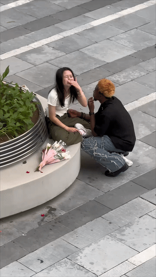 一名女子坐在广场上突然情绪激动的哭了起来。她旁边的黑人男友看到这一幕有点不知所