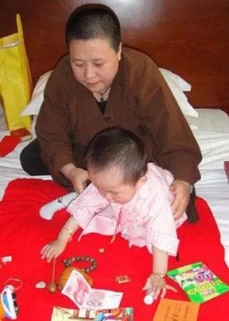 重看网传释永信私生女周岁现场抓周图，意味深长。照片中，眉清目秀的释延洁法师抱着可