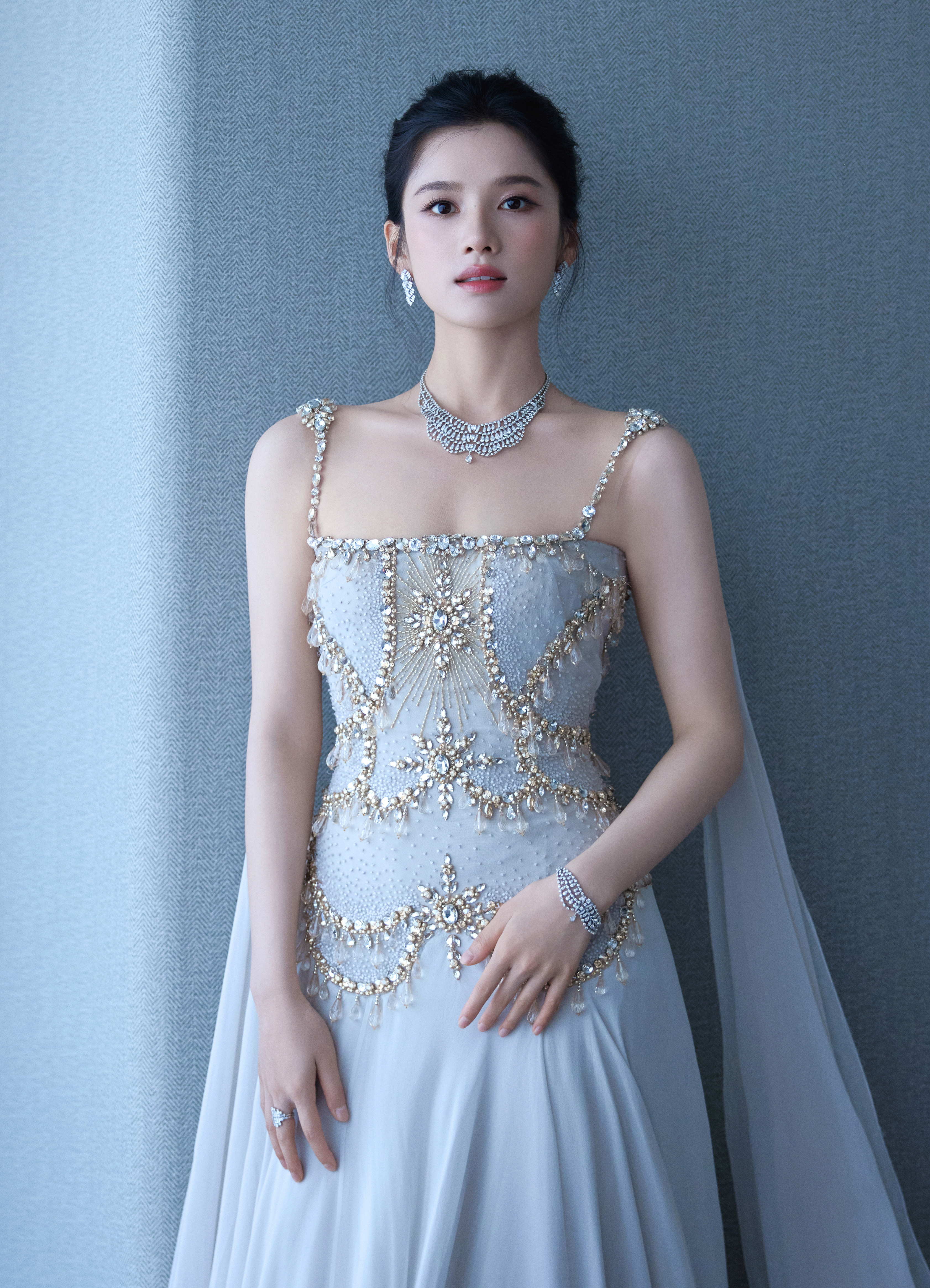 张婧仪. 浅冰蓝吊带高定长裙，鎏金碎钻勾勒鱼骨束腰，垂坠薄纱拖尾，清冷仙气扑面