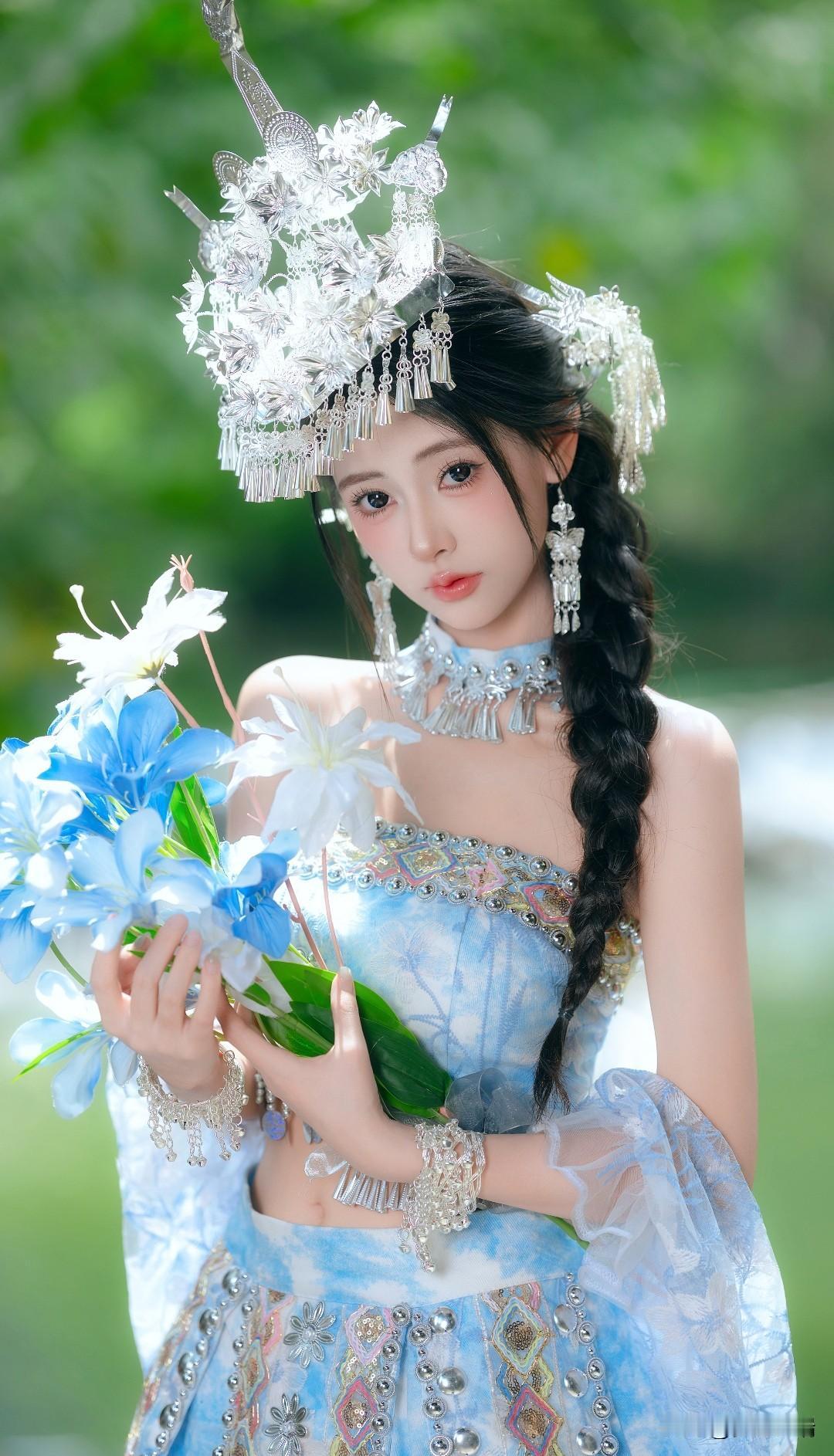 梦幻仙境中的蓝衣民族少女，手持花束，头戴银饰，宛如童话中的公主。
