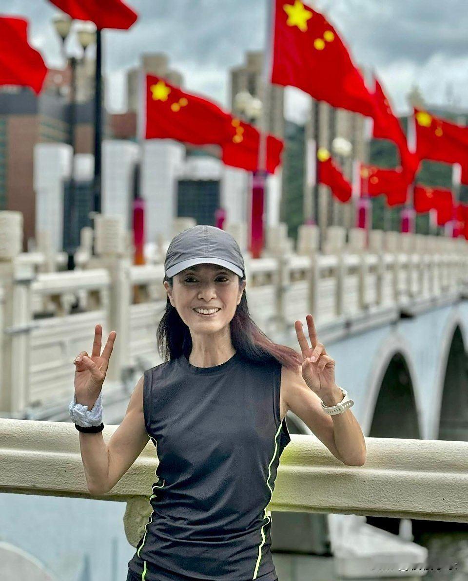 70岁米雪在香港跑步时和五星红旗合影，她看起来好瘦，整个人好干枯，但精神状态挺好