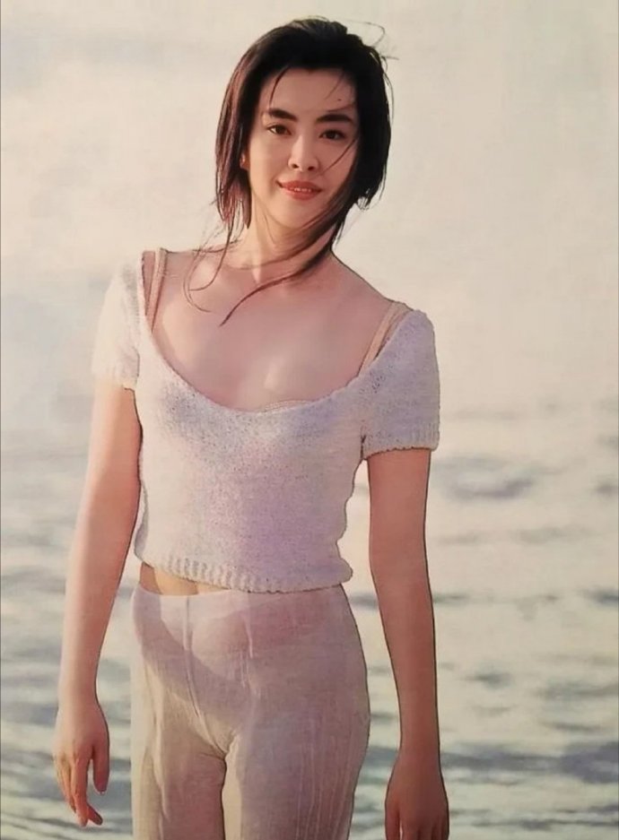 王祖贤年轻时在海边拍的一张留影。照片中王祖贤穿着一身白色的类似瑜伽服的衣服，五官